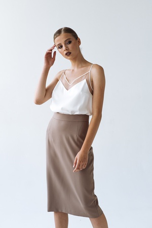 КОСТЮМ ЮБКА ДО КОЛЕН И ПРИТАЛЛЕНЫЙ ЖАКЕТ НА ФОНЕ КАПУЧИНО